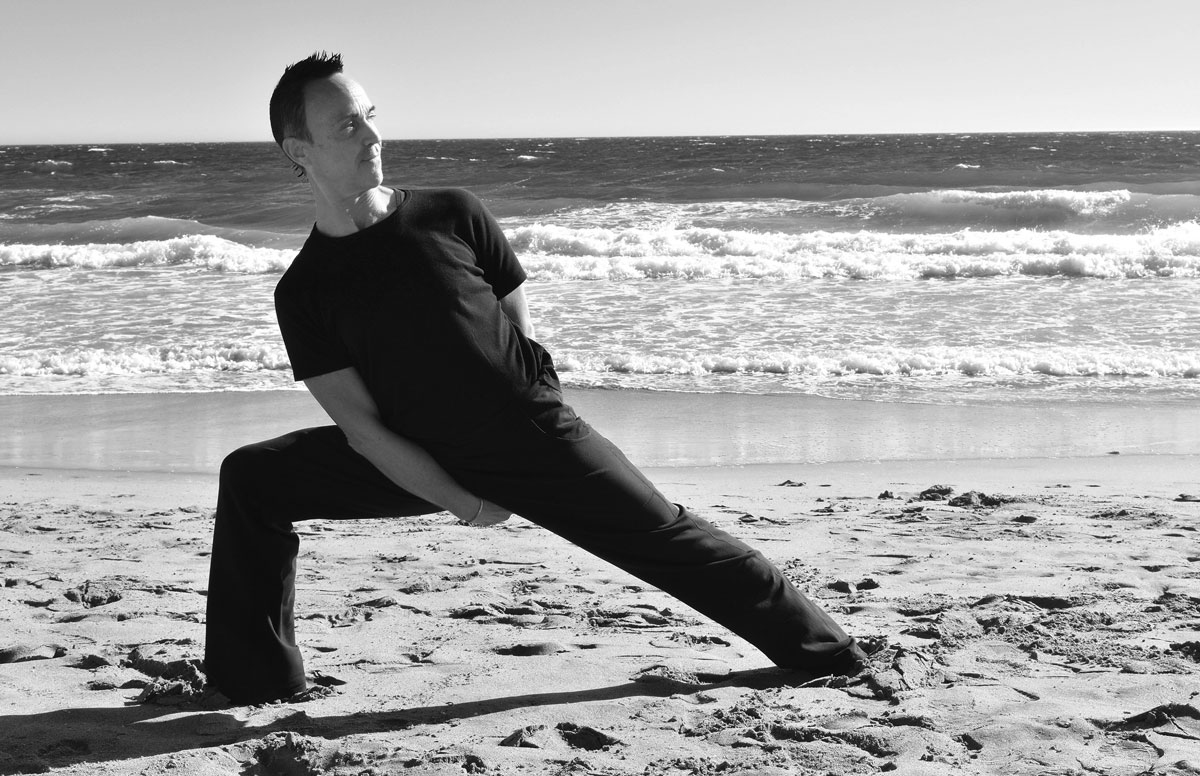 Tom Machado practicing yoga on the beach in Santa Cruz